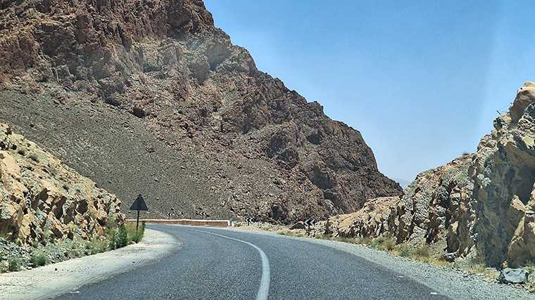 De weg langs hoge rotsen in de buurt van de rivier de Ziz, ten zuiden van Midelt.