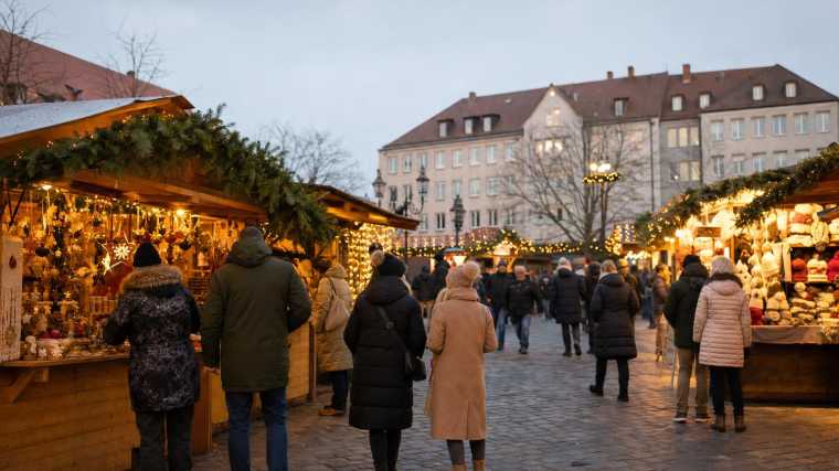 Een stadsplein in Neurenberg met kerstkraampjes, lichtbogen en bezoekers in winterkleding