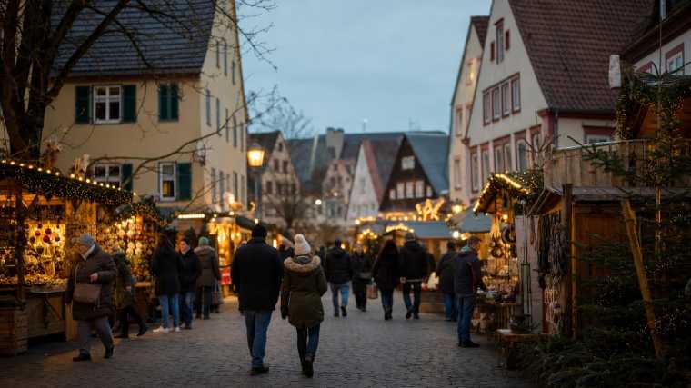 Een kleinere Beierse kerstmarkt tussen historische gevels met lichtslingers in de avond