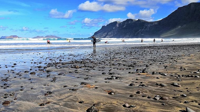 Als de golven hoog genoeg zijn is het heerlijk surfen bij de kliffen van Caleta de Famara, waar je met een huurauto gemakkelijk naartoe rijdt.