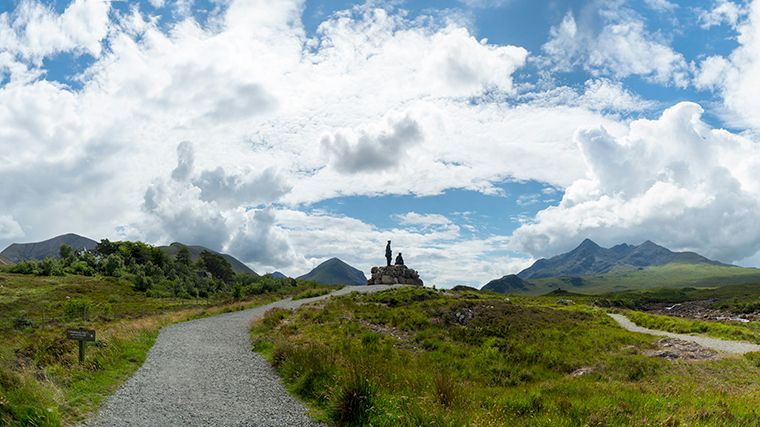 Links de Red Cuillin, rechts de Black Cuillin. Het standbeeld is van twee mannen die het bergbeklimmen in Schotland populair maakten.
