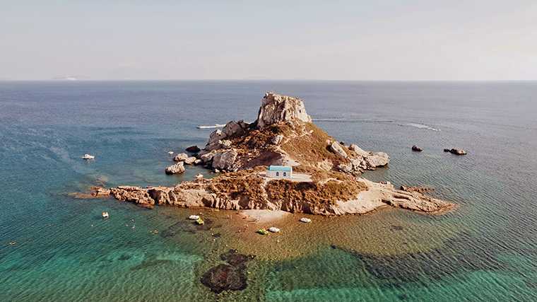 Het rotseilandje Kastri pal voor het strand van Agios Stefanos.