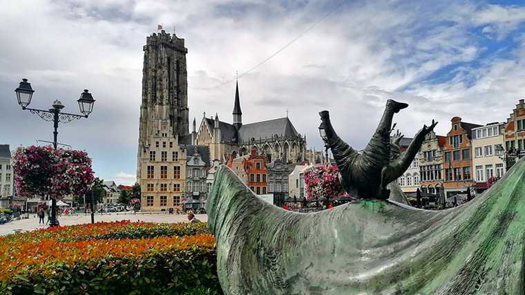 De Sint-Romboutskathedraal in Mechelen met op de voorgrond de folkloristische figuur Opsinjoorke.