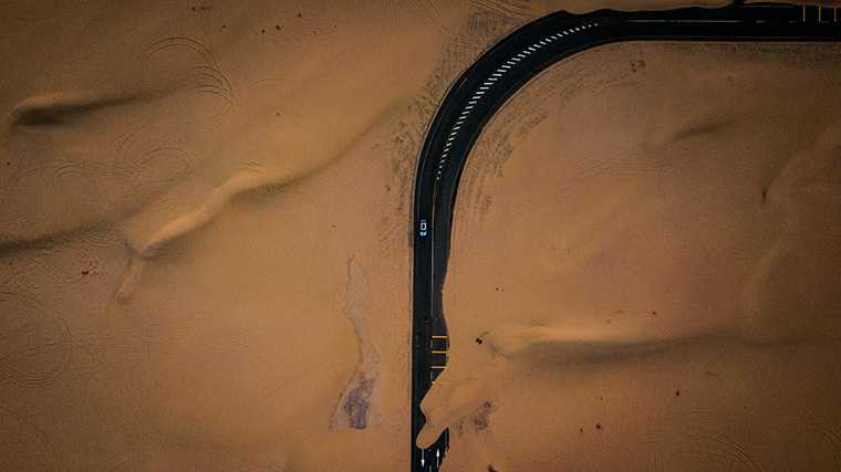 Als je met een huurauto door de woestijn rijdt, moet je er rekening mee houden dat er zand op de weg kan liggen.